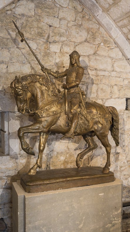 Portrait photograph of the golden Black Prince statue, where the figure of Prince Edward, Prince of Wales, sits upon his horse with a spear raised